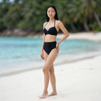 Bikini push up noir Elya 2 pièces — vue 3/4 silhouette galbée, taille marquée sur plage