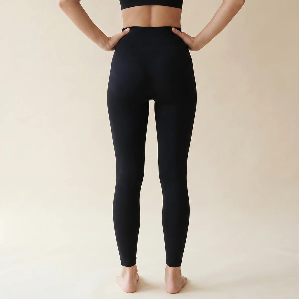 Legging amincissant noir Elya vue de dos, mains sur les hanches — galbe et maintien, taille haute seamless
